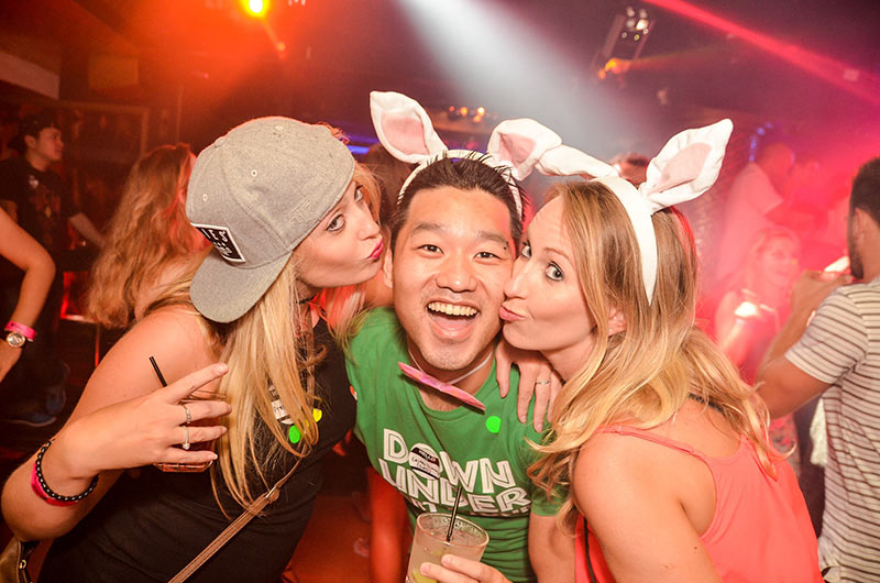 Two girls on the Down Under Easter Weekend party tour in Surfers Paradise last year kissing the party host with bunny ears on